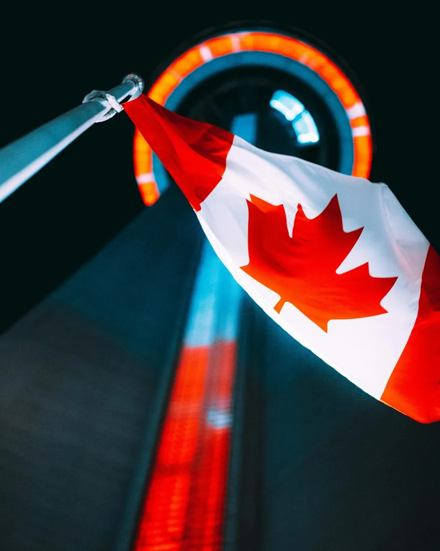 The Canadian flag flying at night in front of a Toronto tower