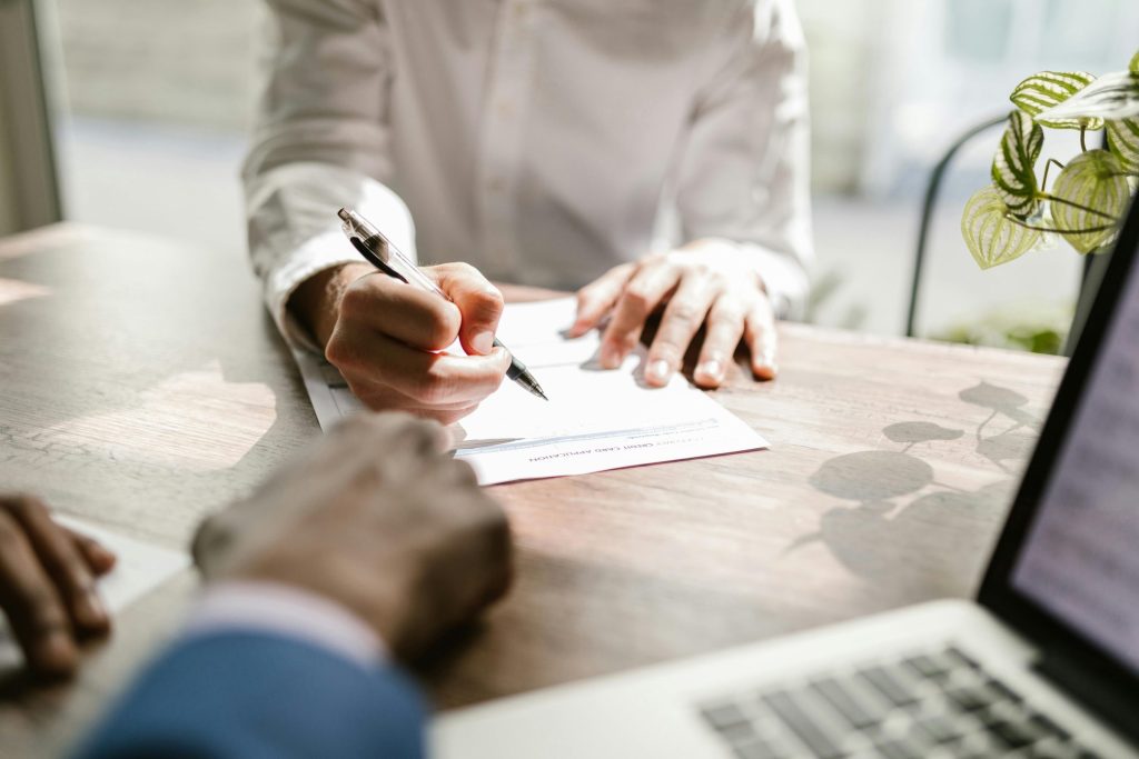 A consultant and a client signing paperwork at a desk
