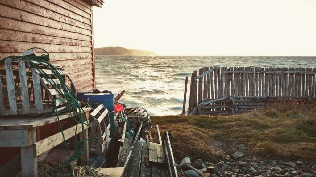A fishing stage with lobster traps on a rocky shore at sunset