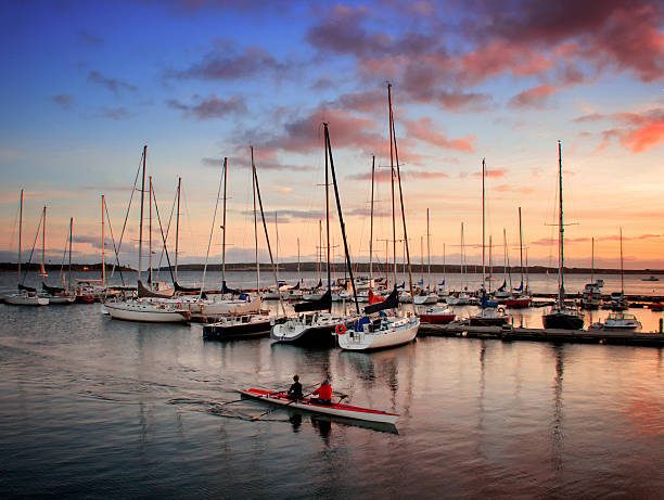 Sailboats moored in a marina at sunset